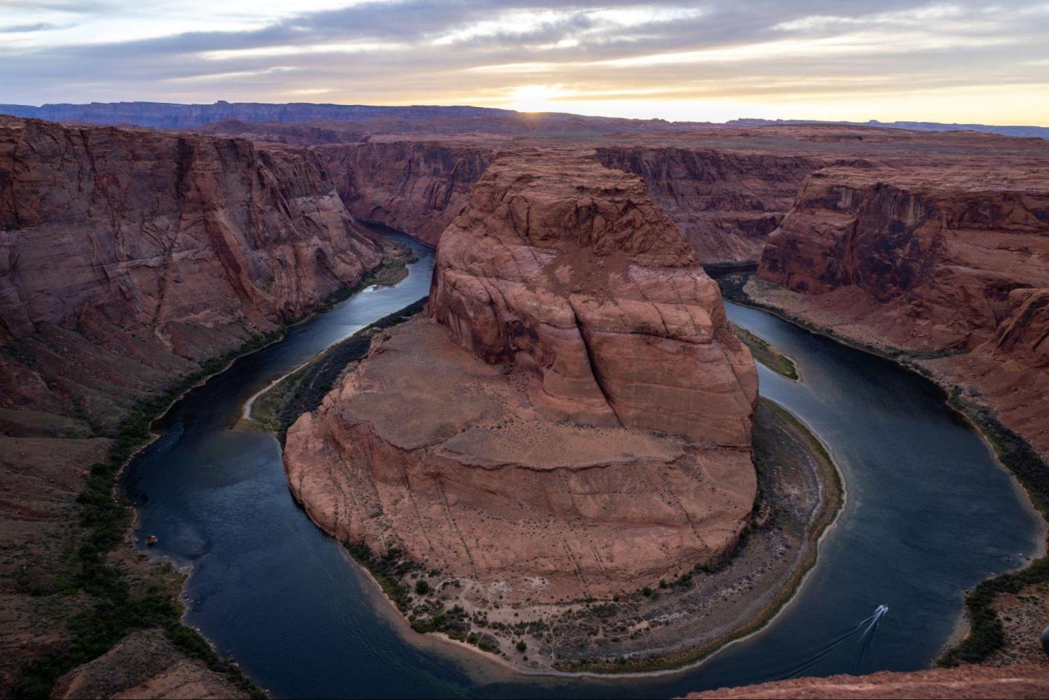 Aerial view of Horseshoe Bend with river curving around rock formation at sunset.