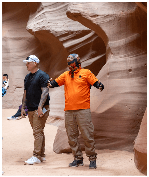 Two people in canyon, one gesturing with arms outstretched.