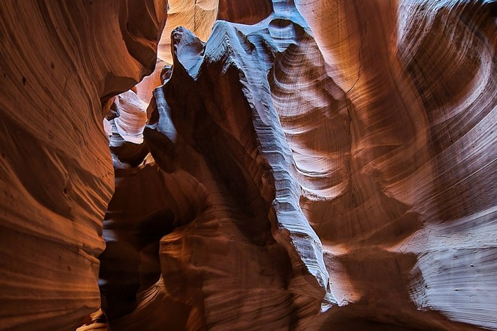 Narrow canyon with smooth, vibrant orange and blue rock walls.